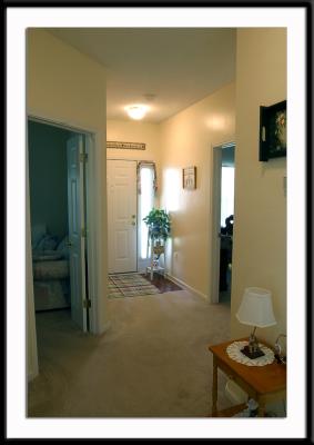 View from dining area down the hall toward the front door of the unit. Den is to the left, guest room to the right, and main bathroom to the far right (just out of view).