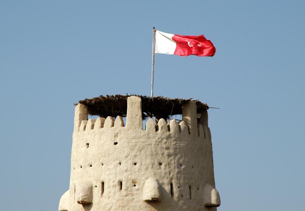 Umm Al Quwain flag flying from the forts largest tower