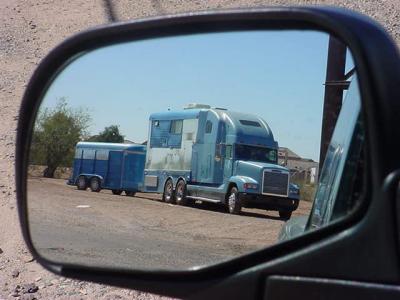 reflection of the big rig with a really neat camper sleeper trailer on the back
