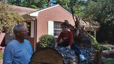 Ben sitting on one of the trees that fell over during Hurricane Isabel while Grandpa watches (Grandpa and Grandma's house in Norfolk, VA)