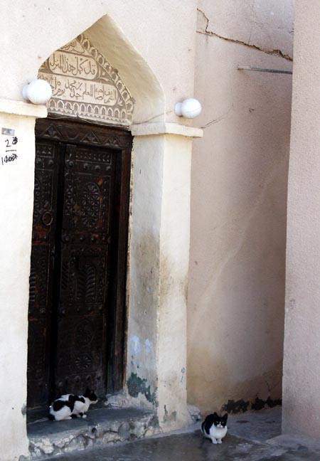Cats in front of ornate door, Rustaq