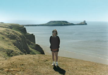 Judy at Rhossili Bay. The Worm's Head rocks (background) is a mile long, serpent-like promontory jutting out into the ocean.