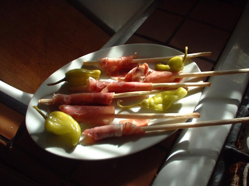 prosciutto garnished breadsticks and pickled pepperoncini