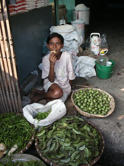 Boy snacking, produce market Dhaka