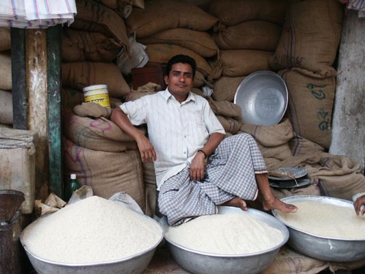 Rice seller relaxing with his wares, Dhaka