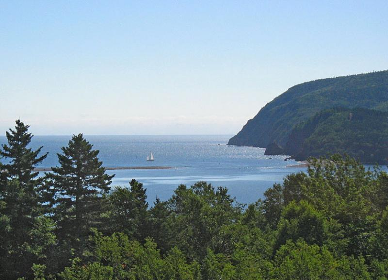 An idyllic afternoon on the east coast of Canada.  Blue skies.  Calm waters.  A sailboat in the distance.