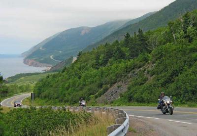 A pair of motorcycles speed up a steep stretch of road.