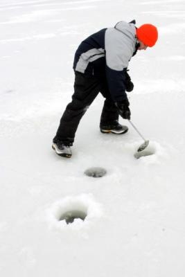 After holes are drilled, the remaining ice in the holes is scooped out with a large spoon with holes in it.