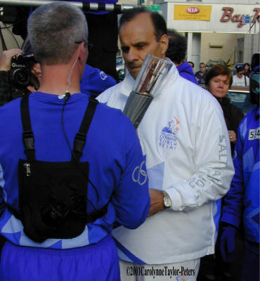 The Olympic Torch is handed over to NY Yankee manager Joe Torre.
