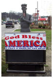 Displayed in a TV repair shop parking lot, this young man actually sits on a tv.