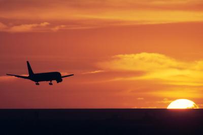 Boeing 767 is approaching runway 28 at sunset.