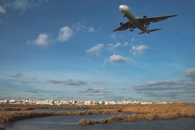 Excel 767 flying over Ria Formosa estuary and Faro city behind.