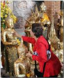 Applying gold leaf to an idol - Wat Chaimongkhon