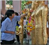 Applying gold leaf to an idol - Prapatom Chedi