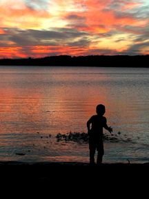 Our son throwing a handful of pebbles into Gunflint Lake