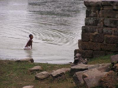 kid playing in water by ruins