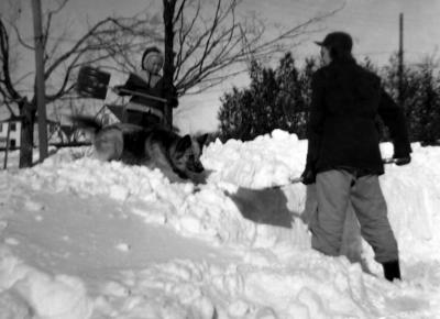 Shovelling snow with the playful dog, early 1960s