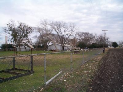 I was standing at the very back of our property, taking a picture down the length towards the front.  The dark green, gumdrop-shaped tree to the right is at the front of our property.  If you look closely behind the bigger of the 2 metal buildings you can see part of our beige house in the background.