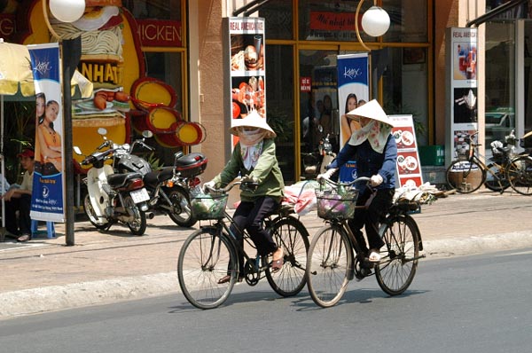 Women in traditional hats on bikes at Saigon Square