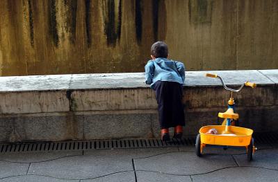 Curious little boy with yellow tricycle