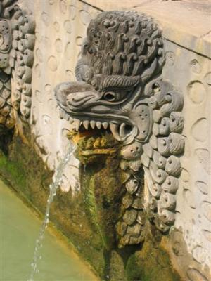 carved stone naga spew water from the natural hot spring into the bath