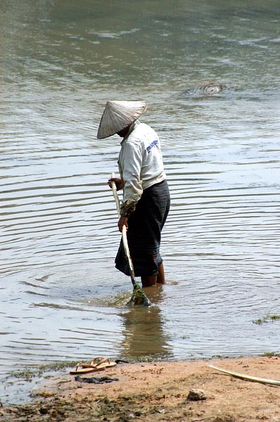 Woman in a traditional SE Asian hat in the moat at Angkor Wat