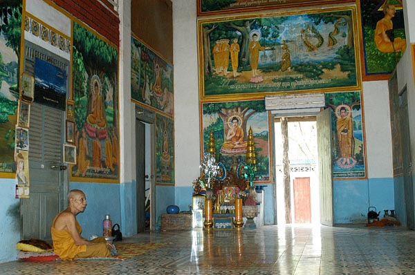 Old monk in a brightly decorated hall near Angkor Wat