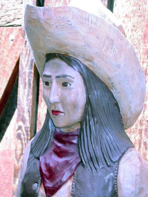A wooden carving of a cowgirl.
