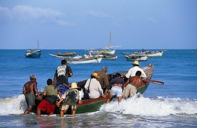 Pescadores entrando no mar na praia do Munda
