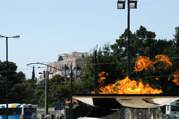 Olympic flame at the stadium in with the Acropolis in the distance