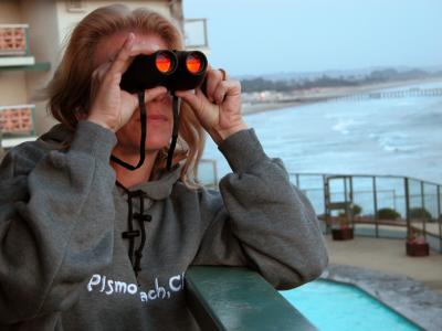 Laurie on the balcony with binoculars at Shore Cliff Lodge. Pismo Beach, CA