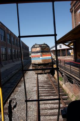 A retired Amtrak loco framed through a caboose's ladder.