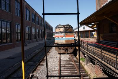 Another shot of a retired Amtrak loco framed through a caboose's ladder. Note the length of the Back Shop on the left.