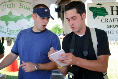 A newspaper photographer takes notes while interviewing one of the Dogfish Head brewers