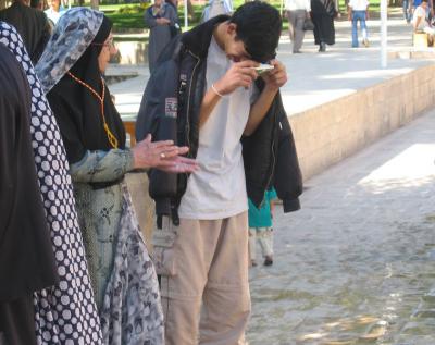 While the woman is probably there for religious reasons,the young boy is interested in photographing the sacred carp.