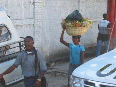 woman with basket of veggies on her head and the front part of an UN truck