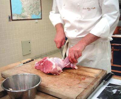 Chef demonstrating how to trim veal