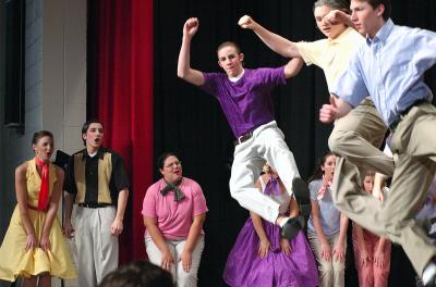 Aaron jumps high in Pajama Game dance routine (Becca at far left)