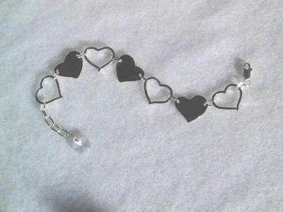 This sweet bracelet features solid and open (floating) sterling hearts with a crystal heart dangle.  Sold