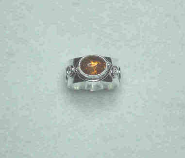 Front view of Jamie's amber ring.  The stone is framed by curved wire and silver beads.