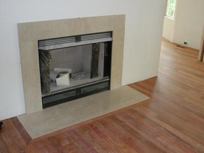 The marble fireplace surround in place with hearth framed by cherry