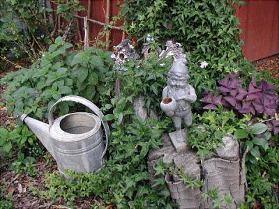 An old watering can, a pewter elf and some bird houses