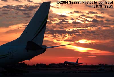 Tail of Miami Air International's B737-8Q8 N734MA on the ramp with American B757 landing at sunset aviation stock photo #2679