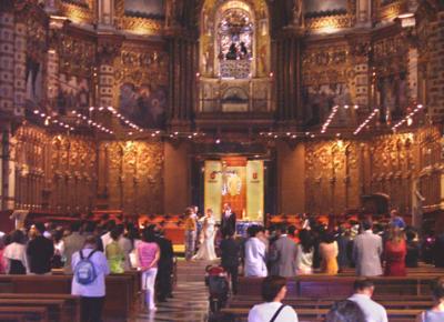 A wedding inside the basilica. Above the altar, people can be seen passing by the statue of La Moreneta (The Black Virgin).