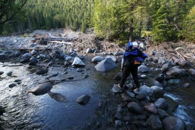 Carol using boulders to cross a creek