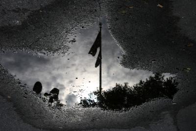 Flags Reflected in a Puddle of Water