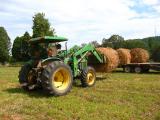 John Deere tractor putting hay on a trailer