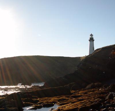 Oregon Coast Lighthouse from beach with suns rays.jpg