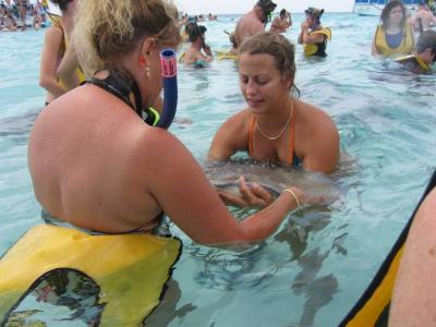 Two women hold a male stingray