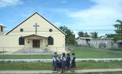 Children walking home from school past a church in Belize
